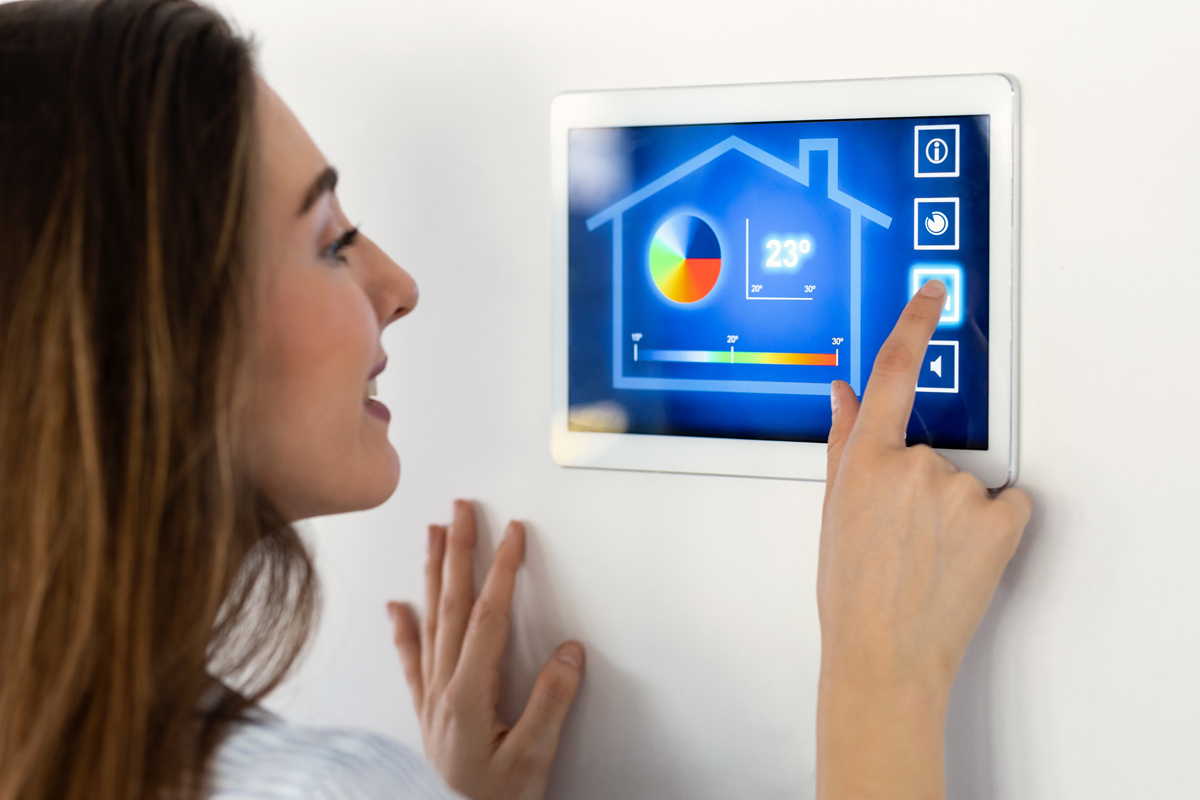 Pretty young woman using the home automation system on digital t